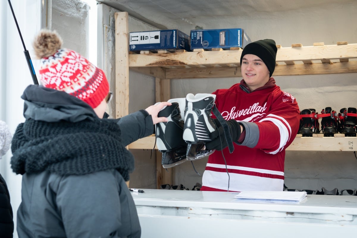 Un commis qui prête des patins à un usager